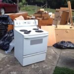 Appliance Removal Services Kent WA showing an old electric stove, furniture, and household junk placed curbside for professional appliance pickup and disposal.
